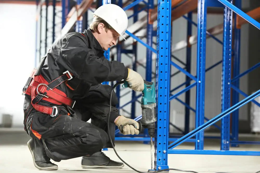 Industrial worker using power tool during warehouse mezzanine installation